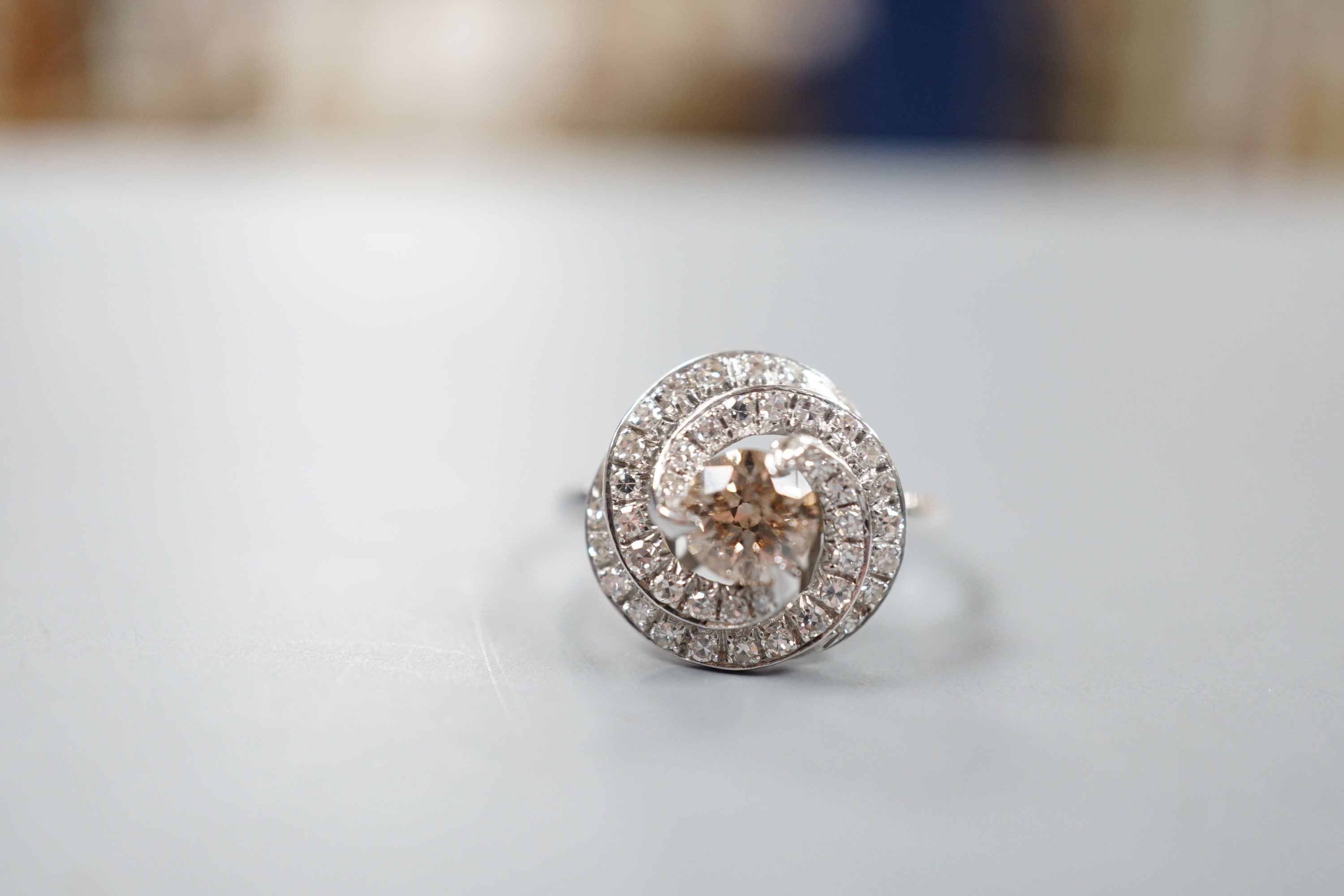 A French white metal(18ct poincon mark) and cognac coloured single stone diamond ring, with diamond set spiral cluster setting, size S, gross 5.5 grams.